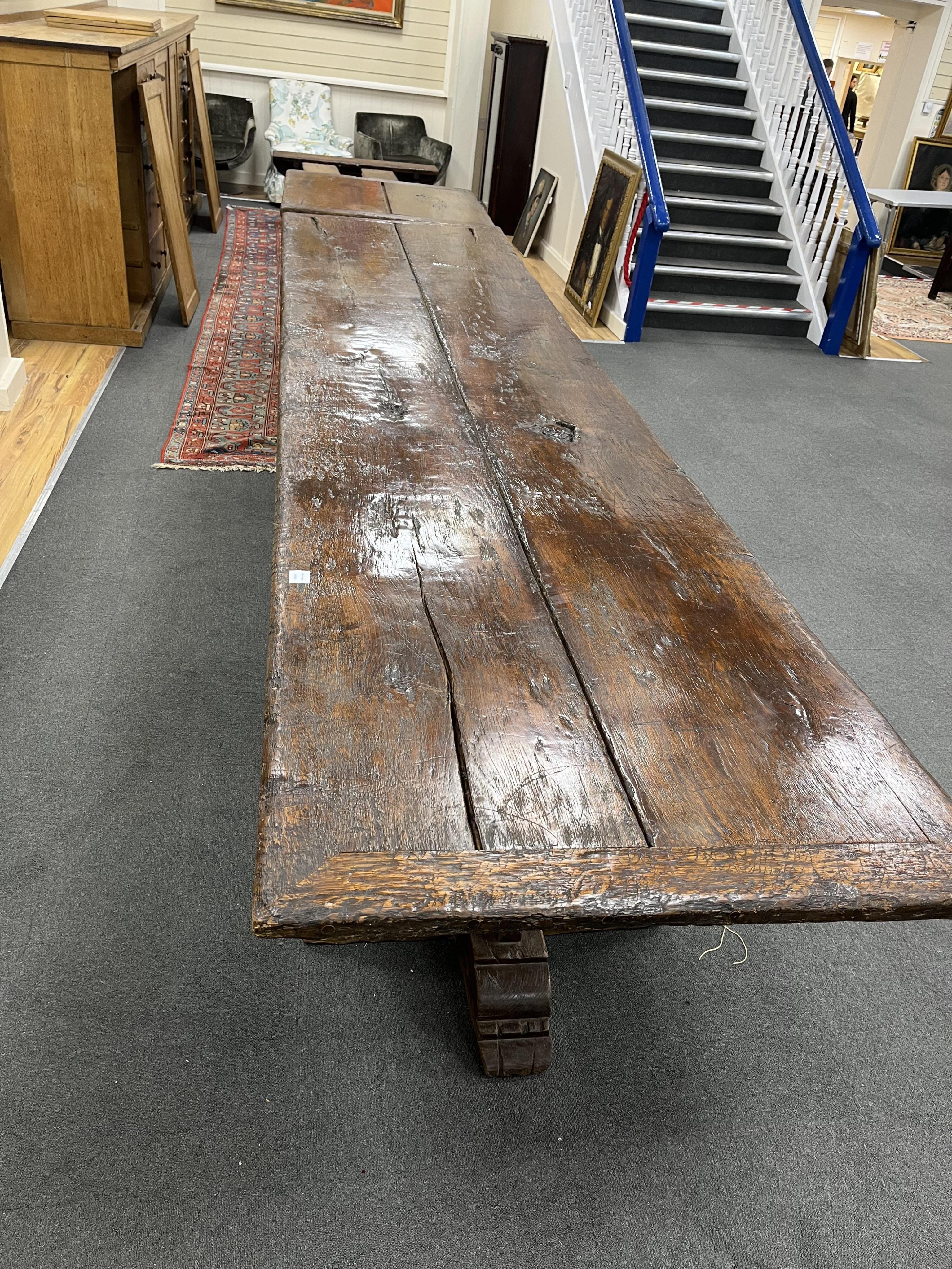 A long twin plank oak refectory dining table, in 15th century gothic style, cruciform twin pedestal base, with additional square extension table, length 365cm, 464cm with extension, depth 88cm, height 78cm. Condition - f